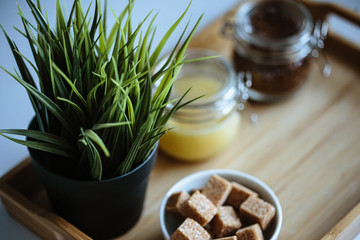 Wooden tray with tea cup and honey in a glass, cozy morning composition