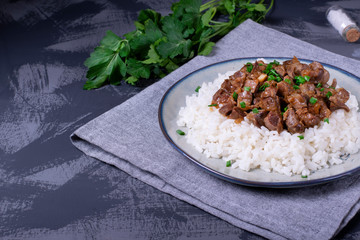 Stewed chicken gizzards on the boiled rice. Hot meal with offal meat products