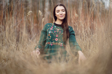 Hands of a girl meditating in a yoga pose on the grass. Woman practices yoga and meditates in the lotus position on the grass field. Young attractive slim girl relaxing and doing exercises. 