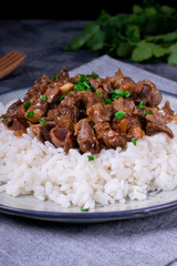 Stewed chicken gizzards on the boiled rice. Hot meal with offal meat products