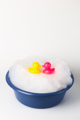 Pink and yellow baby ducks swim in a foam basin. Summer concept.