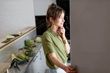 Young woman looking into the fridge, feeling hungry at night