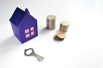 Paper house, key and money coins on a white background