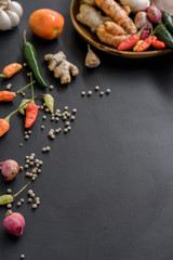 Basic ingredients of seasoning in a wooden plate. Some spices photographed scattered on a black background.