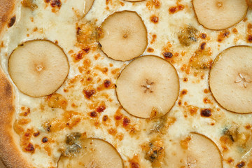 Appetizing baked pizza with white sauce, pear, and gorgonzola cheese with crisp on a wooden background. Restaurant table setting. Top view, close up texture