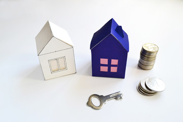 Paper houses, key and money coins on a white background