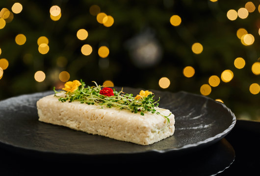 Elegant appetizer of white fish pate with edible flowers on black plate