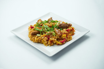 Tasty wok rice in sweet and sour sauce with vegetables and beef in a white plate on a gray background. CLose up