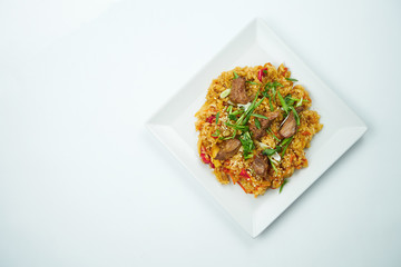 Tasty wok rice in sweet and sour sauce with vegetables and pork meat in a white plate on a gray background. Top view with copy space
