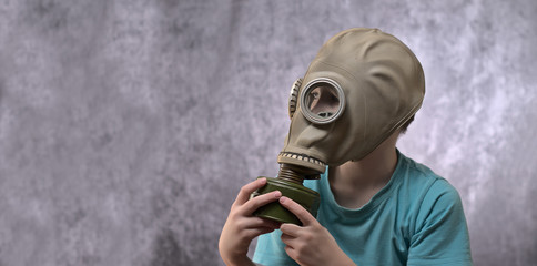 The boy is sitting in a gas mask. Protect from Coronavirus COVID-19
