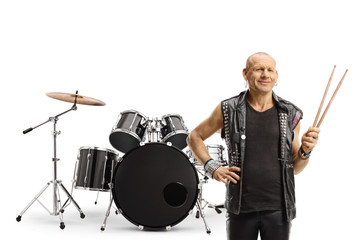 Rock music drummer holding a pair of drumsticks and posing with a drum set