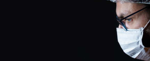 Extreme close-up portrait of a man wearing surgical mask an hair plastic hat on a black background with copy space available