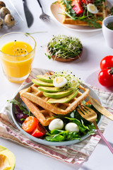 Breakfast time. Waffle with salad, egg, juice and avocados for breakfast. View from above.