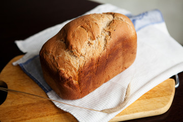 Freshly baked bread with golden crisp on towel and wooden cutting board