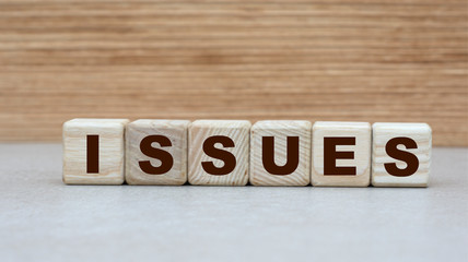 concept of the word ISSUES on cubes on a wooden background