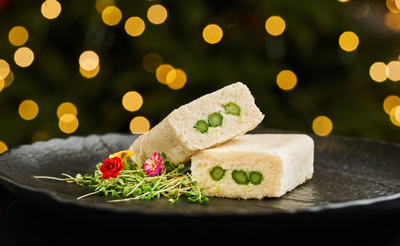 Elegant appetizer of white fish pate with edible flowers on black plate