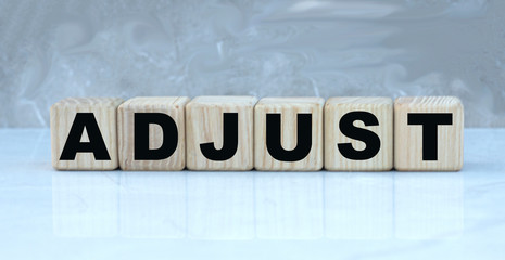 concept word ABJUST on wooden cubes on a beautiful gray background