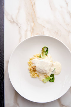 Fusion dish of baked cod with Beurre Blanc sauce, Israeli couscous and grilled vegetables