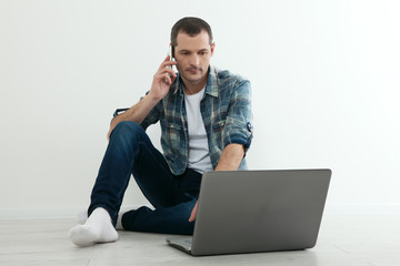 Happy man sitting on floor in his new home. Work from home concept