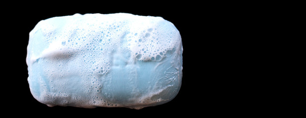bar of soap with foam bubbles on black background. Top view.