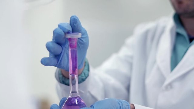Scientist working with chemical reaction in chemistry research lab. Chemical reaction in glass flask. Lab worker doing chemical experiment in laboratory