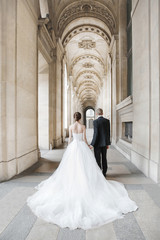 Bride and groom having a romantic marriage in Paris. Wedding couple near the Louvre Palace. Romantic walk through Paris in a beautiful wedding dress. Wedding ceremony in France. View of the Pavillons