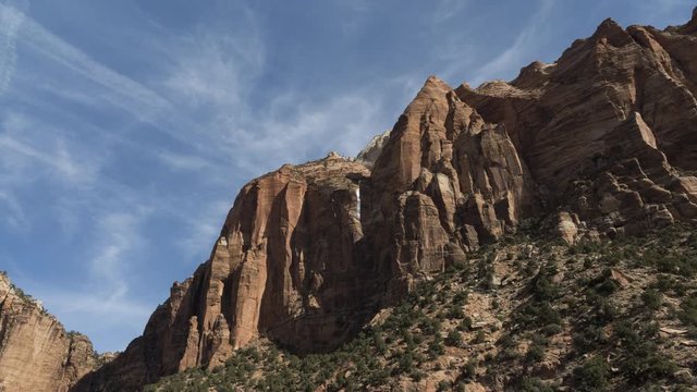 A motion timelapse panning around from looking at red cliffs in Zion Canyon to looking up Pine Creek towards Canyon Overlook as wispy high cloud flows overhead.
