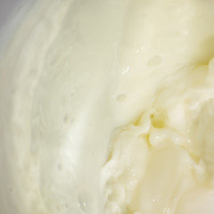 Splashes of liquid milk on a square background is macro
