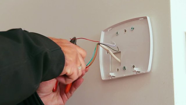 Technician installing or repairing alarm of a smart home security system. Door sensor for burglary prevention. Close up low angle on his hand.
