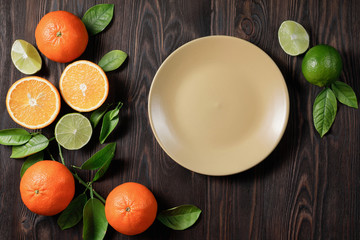Table setting with yellow trendy ceramic plate and healthy fresh fruits on wooden background. Trendy dark mood. Flat lay image with copy space. Top view