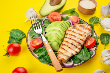 Grilled chicken breast with avocado and herbs on a bright yellow background. Ketogenic diet. Dietary nutrition. Side view. Close-up.