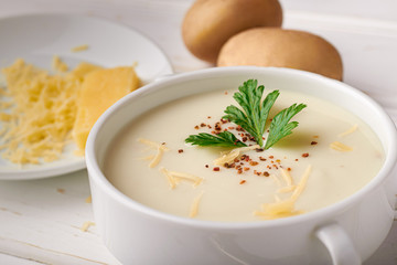 Potato soup with cheese and raw potatoes on the table