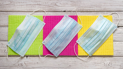 Face medical masks to prevent covid-19 virus infection on multi-colored background.