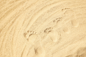 Fototapeta na wymiar A Drawing in the sand near the sea in nature travel background. Hand drawn footprint on vacation.