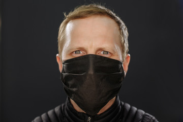 In a black mask. Quarantined man. On a black background. Quarantine covid-19. Stay at home.