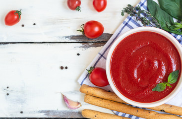 tomato soup with basil, breadsticks on white background 