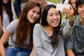 Happy young group of friends taking selfie together at the park
