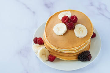 breakfast, pancakes with raspberry, banana and blackberry on a white plate