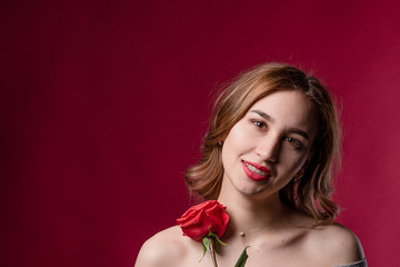 Portrait of a beautiful girl with bare shoulders and a rose. The concept of youth, beauty and a healthy body