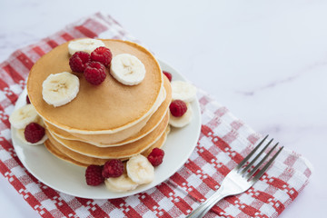 breakfast, pancakes with raspberry and banana on a white plate