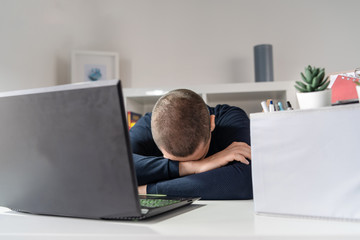 Front view on caucasian adult sitting by the table at office having his box with personal items belongings packed after being fired from job dismissed at work due to economic crisis and recession