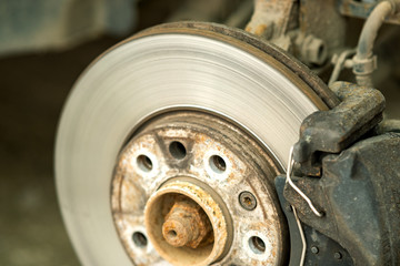 Closeup of braking disc of the vehicle with brake caliper for repair in process of new tire replacement. Car brake repairing in garage.