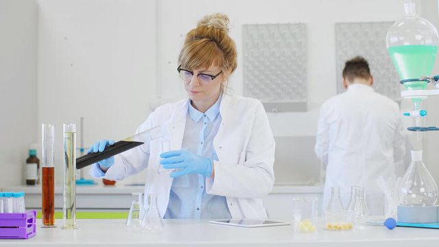 Chemist working with hemp CBD oil and tablet in laboratory