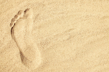 Fototapeta na wymiar A Drawing in the sand near the sea in nature travel background. Hand drawn footprint on vacation.