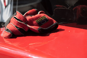 Gants rouges pos&eacute;s sur une voiture de course 