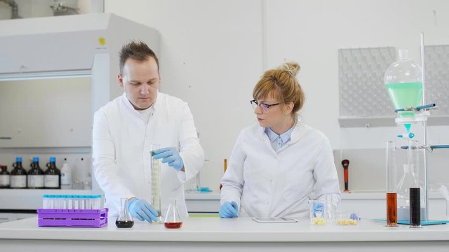 Chemist working with hemp CBD oil and tablet in laboratory