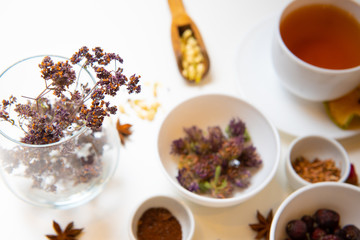background of dried flower in a glass vase and blurry ingredients of healing herbs on a white table
