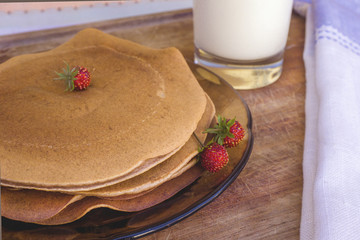 Homemade pancakes with strawberries and glass of milk onrural wooden table with linen serviette. Concept of healthy breakfast.