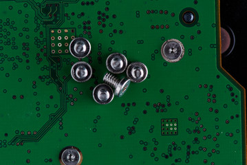 Screws for assembling a computer, photographed in close-up on an electronic circuit board.