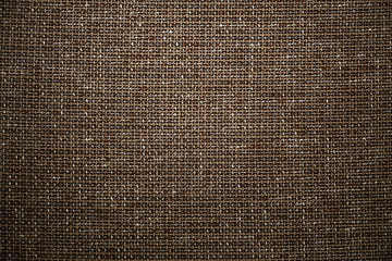 Brown textile fabric background. High resolution close up of brown fabric cloth made of various textile threads. This top view dark fabric background can be used as design element such as backdrop.